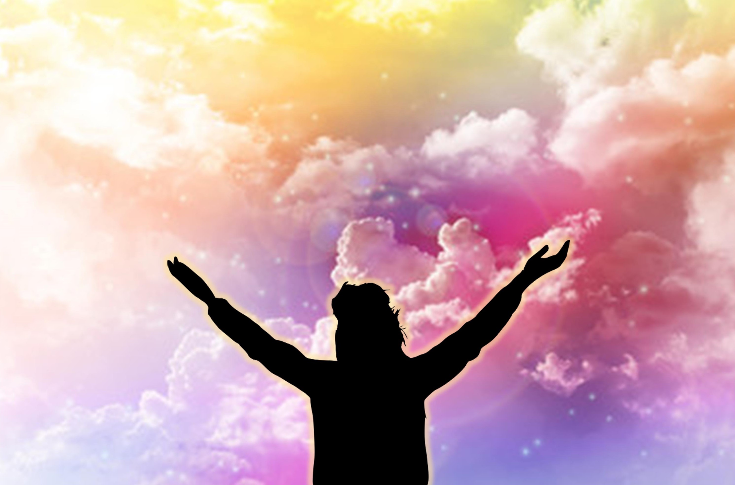 Shadow of figure with arms raised toward pastel clouds.